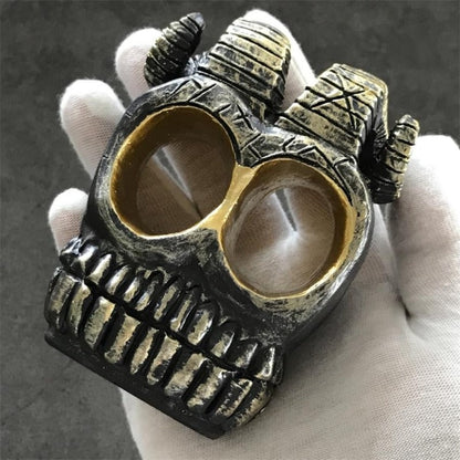 Skull ram horn knuckle duster front view antique bronze finish held in gloved hand