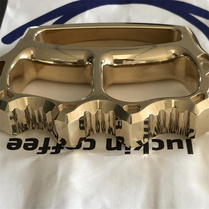 Brass knuckle duster held in white gloved hand showing size