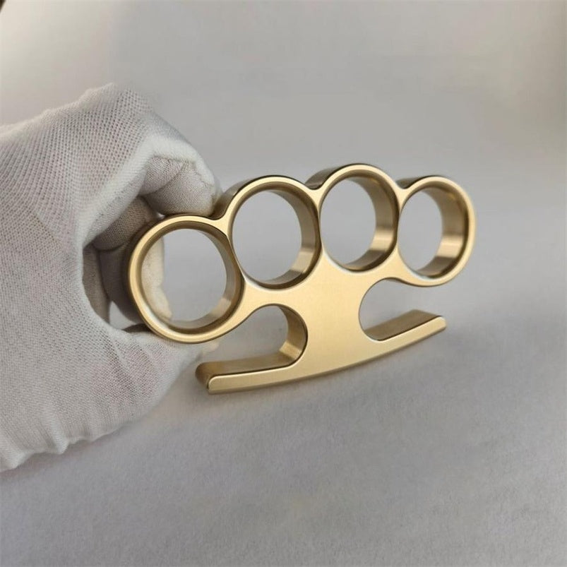 Hand in white glove holding solid brass knuckle duster side view