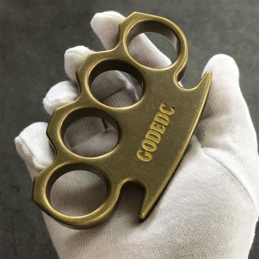 GODEDC solid brass knuckle duster front view with four finger holes and engraved logo held in gloved hand