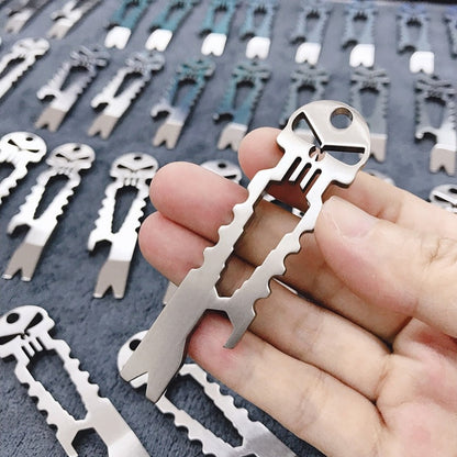 Hand holding titanium skull multi-tool showing wrench slots and skull design