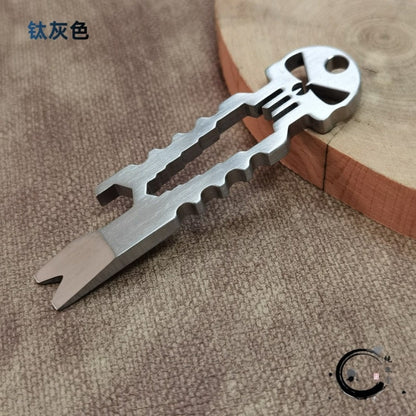Gray titanium skull multi-tool with size measurement markings on fabric background